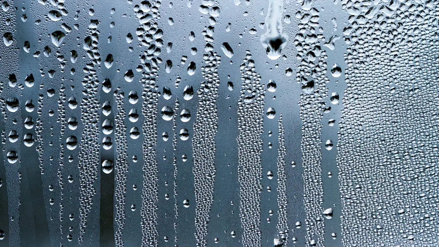 Condensation droplets covering a cool glass surface