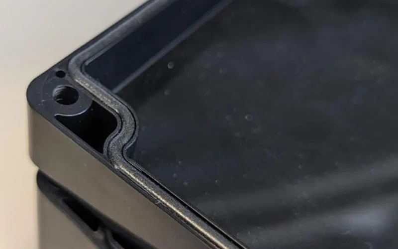 Moulded gasket seated in the groove of a plastic enclosure lid