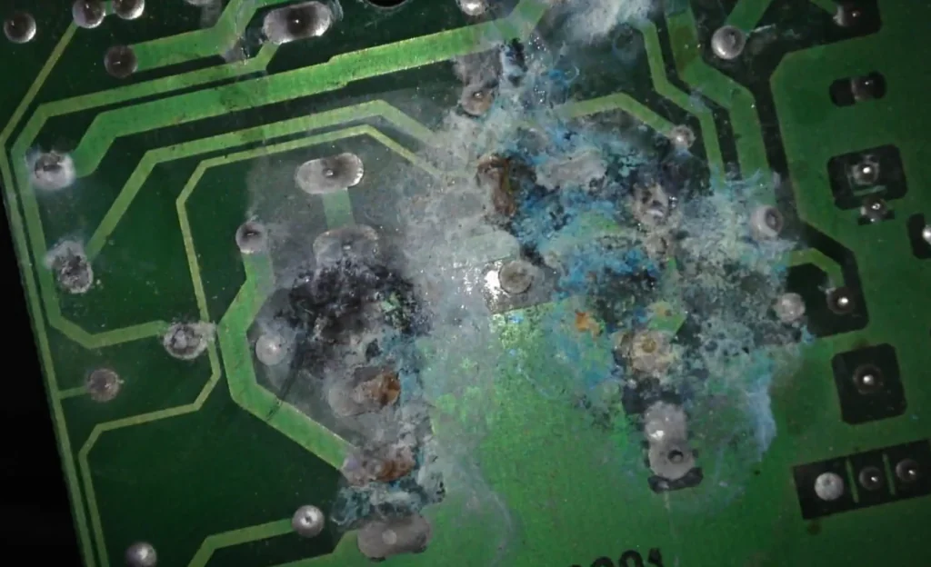 Circuit board with visible corrosion and residue around component pads